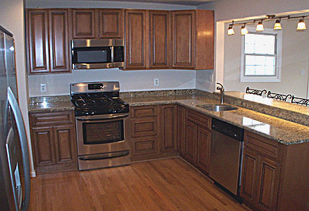 Assembled kitchen cabinets in combination with wood floor, stone countertops and stainless steel appliances