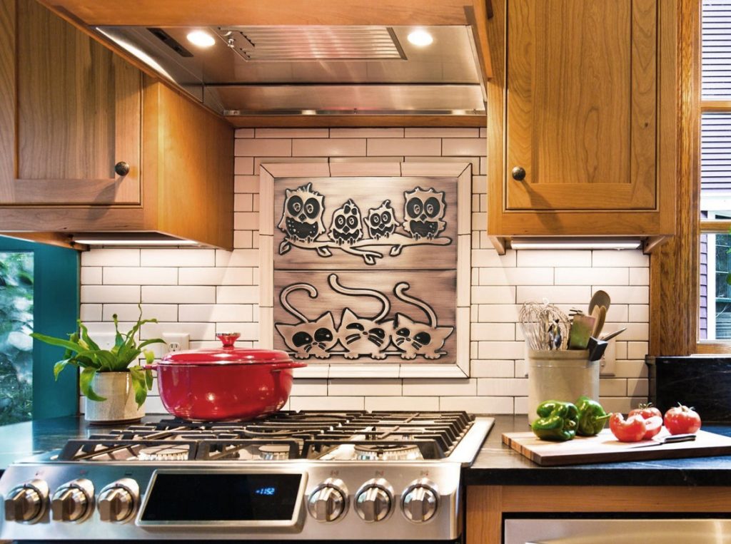 Stainless steel backsplash representing family of owls on a branch and also cats